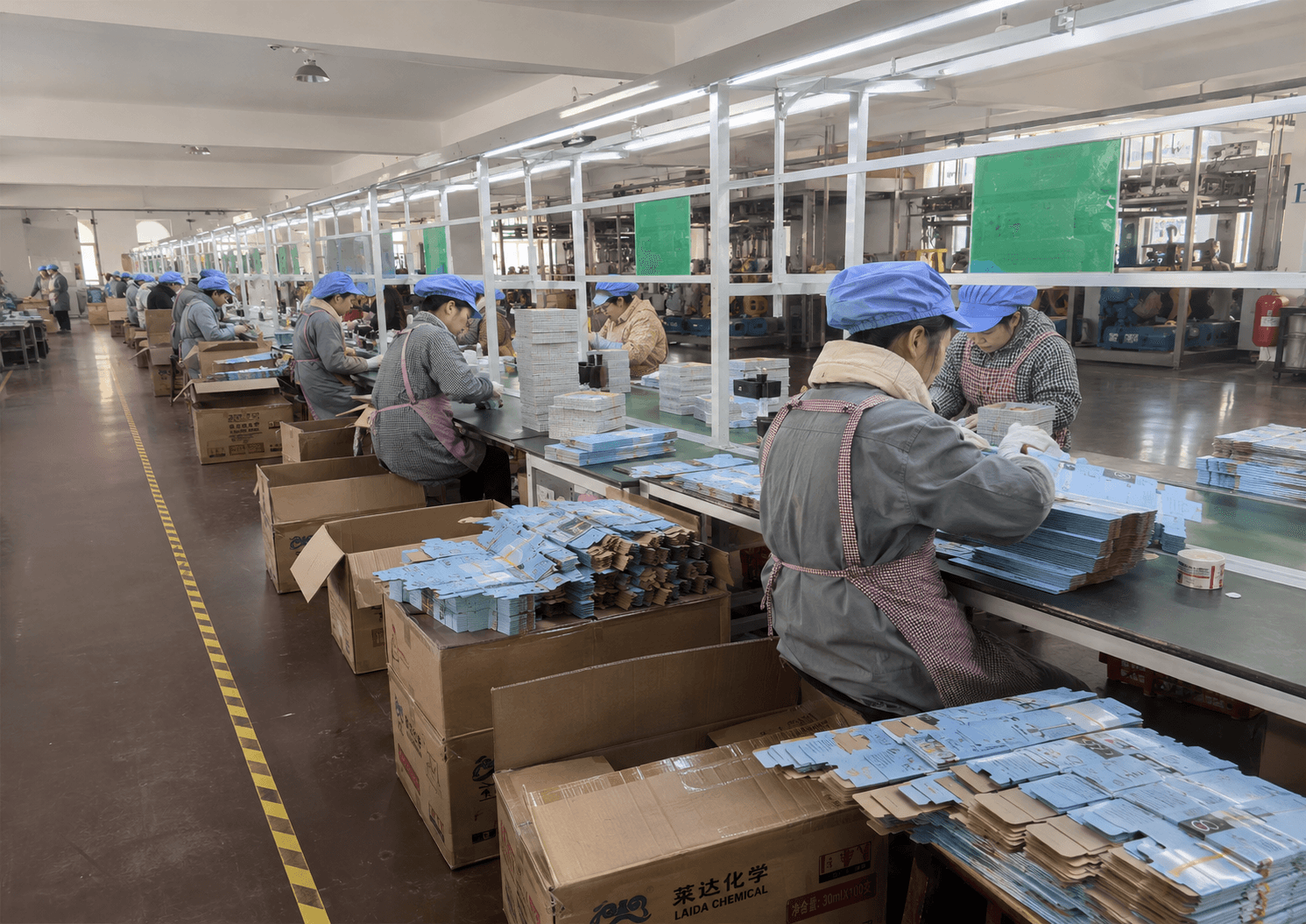 Workers forming and packing printed color boxes on a small-appliance production line